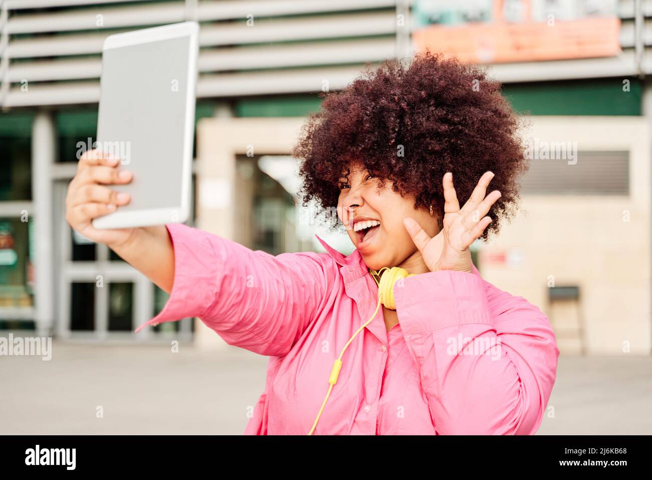 donna afroamericana con capelli ricci che prende un selfie con un tablet pc. giovane donna che ondola mentre fa una videochiamata. Foto Stock