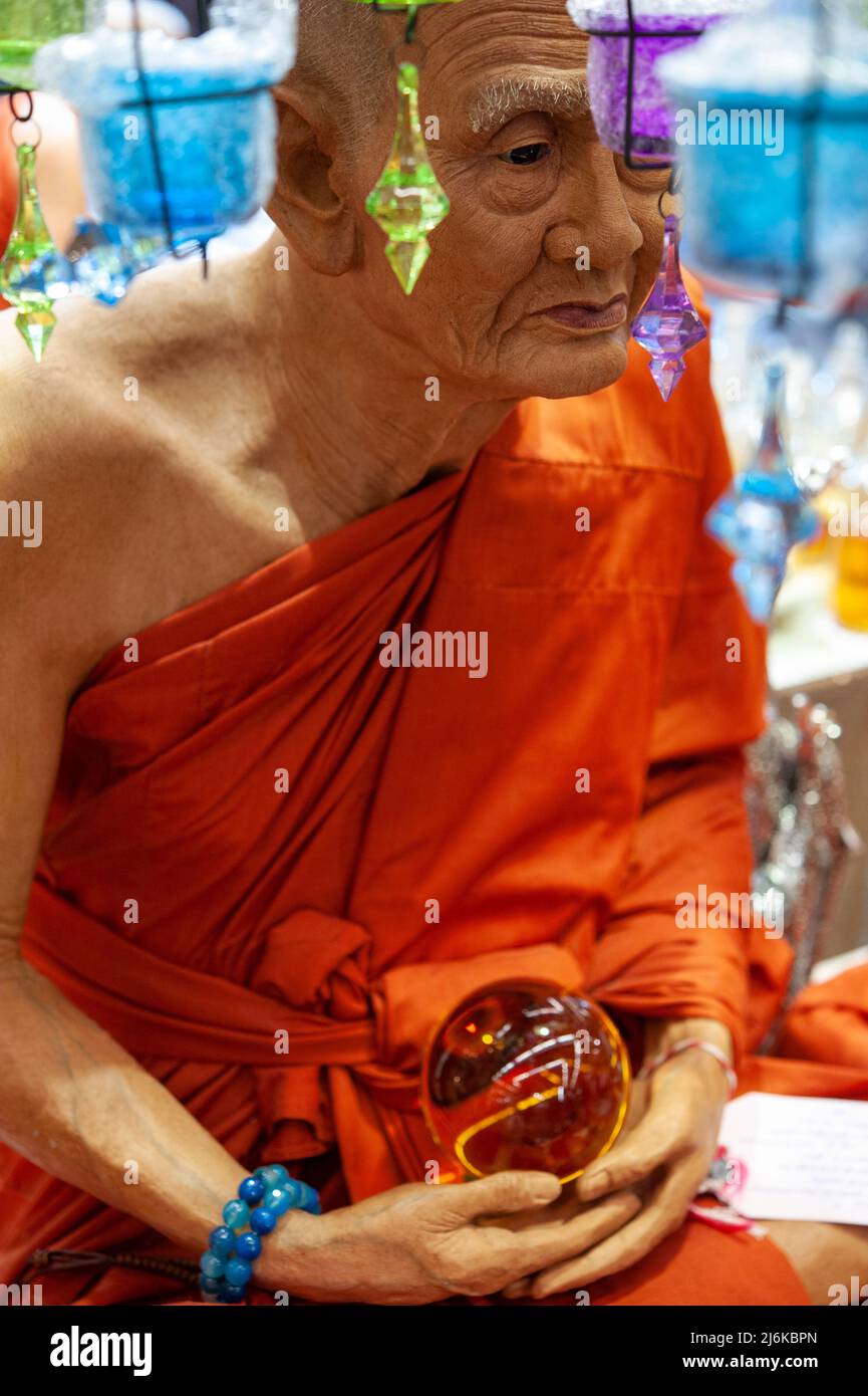 Monaci buddisti, marionetta a grandezza naturale, in abiti arancioni, con una sfera di cristallo nelle sue mani, seduto in meditazione su una bancarella del mercato Foto Stock