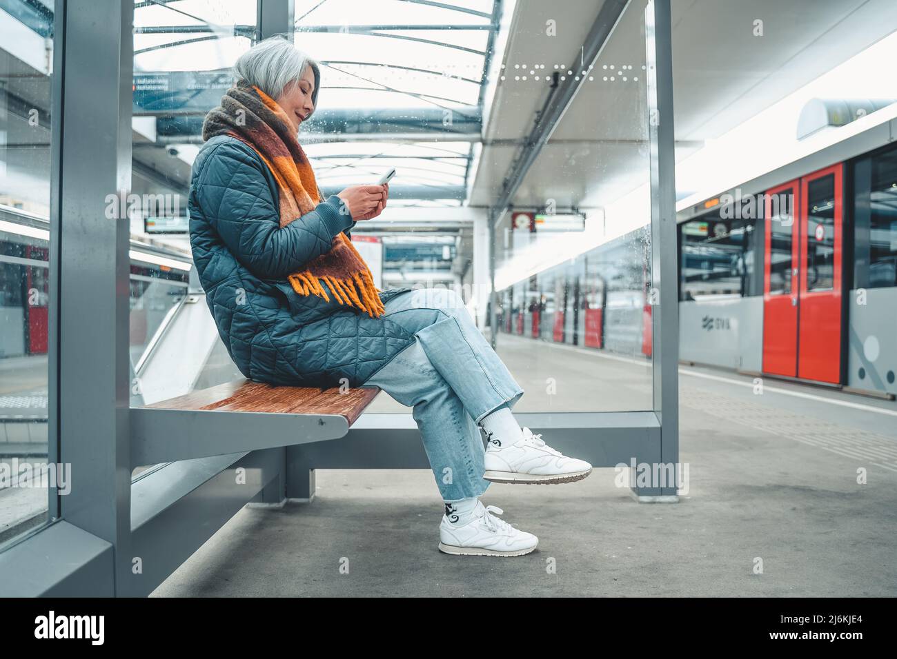 La donna anziana acquista il biglietto del treno con lo smartphone Foto Stock