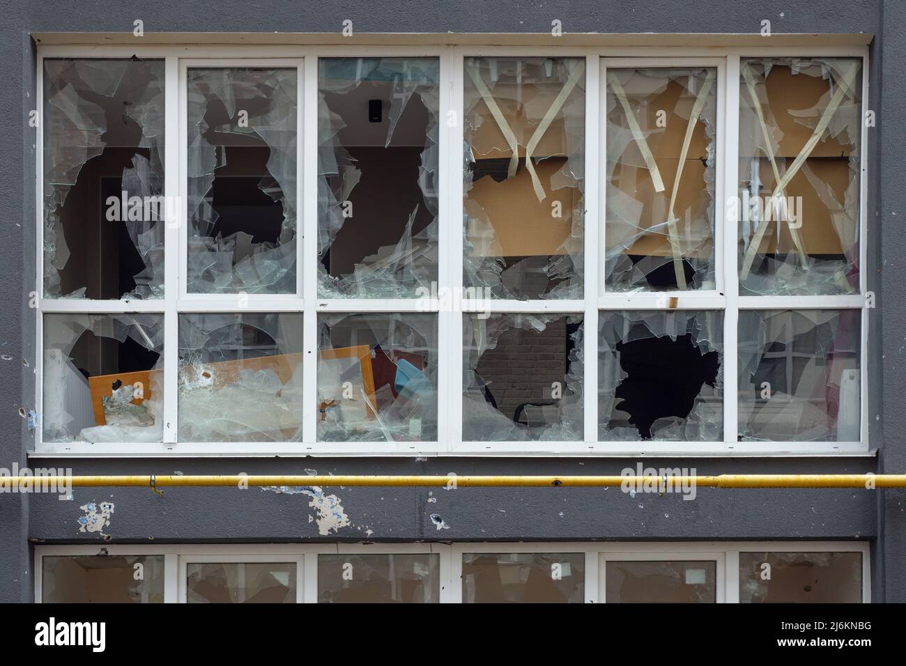 Finestra schiacciata rotto vetro rottura. Distrutto edificio rotto telaio plastica finestra. Aftermath bombardato finestra edificio infrangere vetro danni edificio Foto Stock