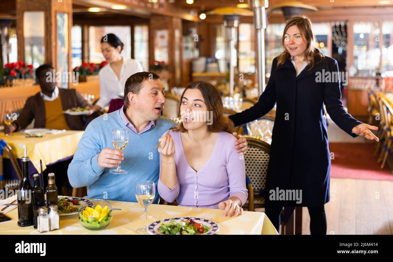 Moglie che scolding marito trascorrere il tempo con un'altra donna al ristorante Foto Stock