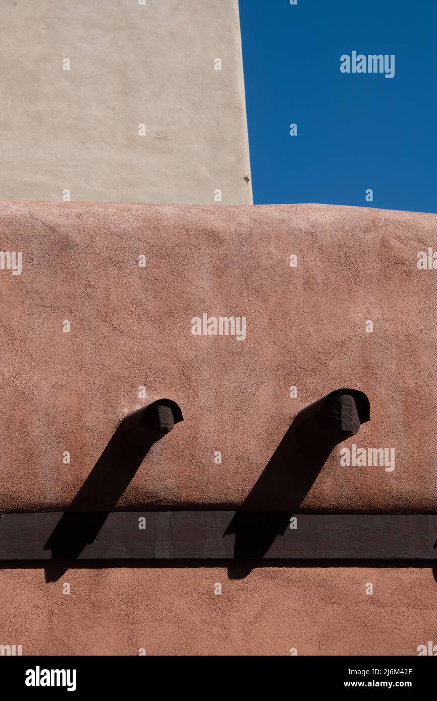 Grandi travi di legno che sporgono da parete esterna di calcestruzzo della casa o della casa di adobe a Santa Fe, New Mexico, U.S.A. costruzione di architettura di Adobe Foto Stock