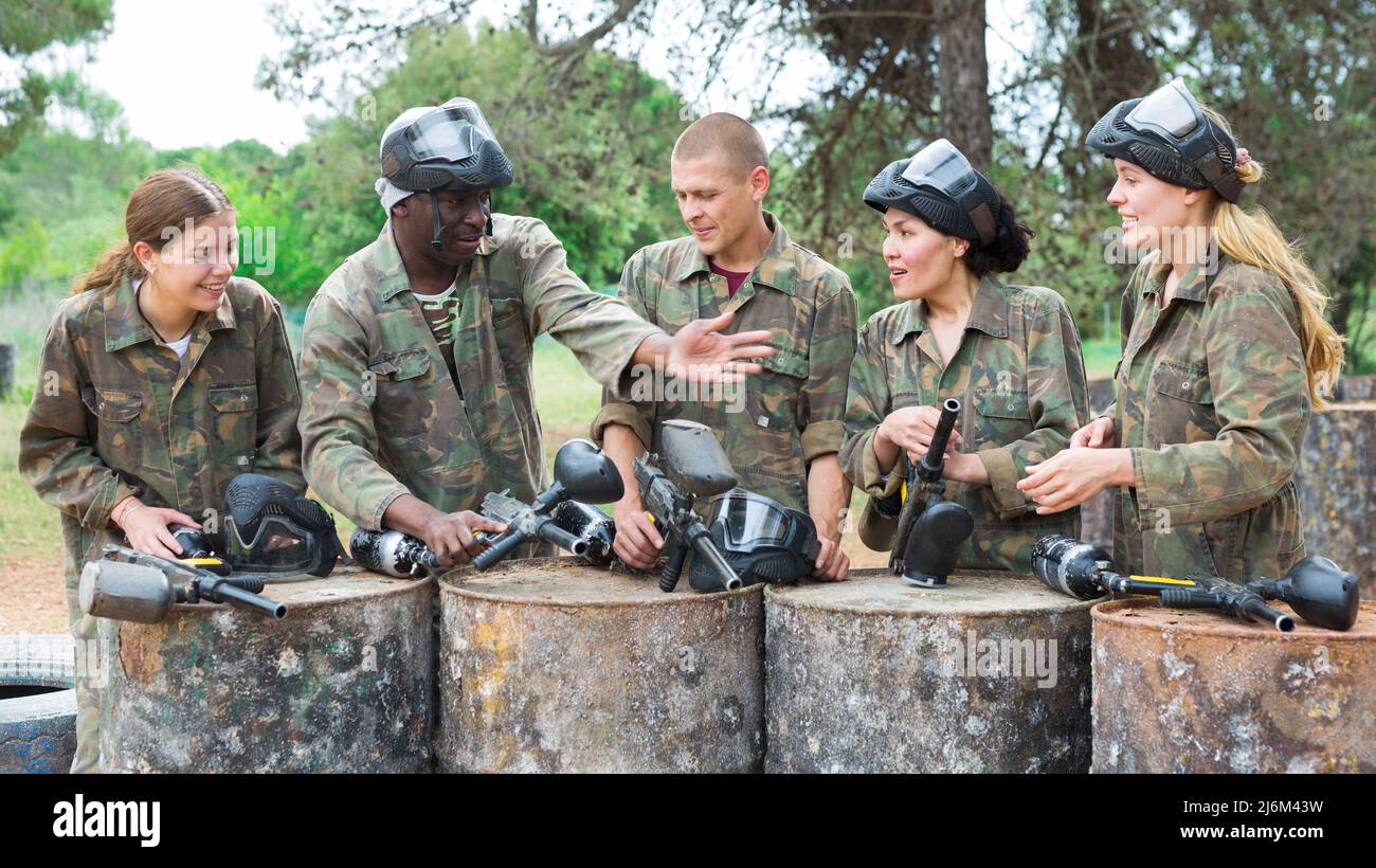 Amici sorridenti che chiacchierano dopo un successo paintball match Foto Stock