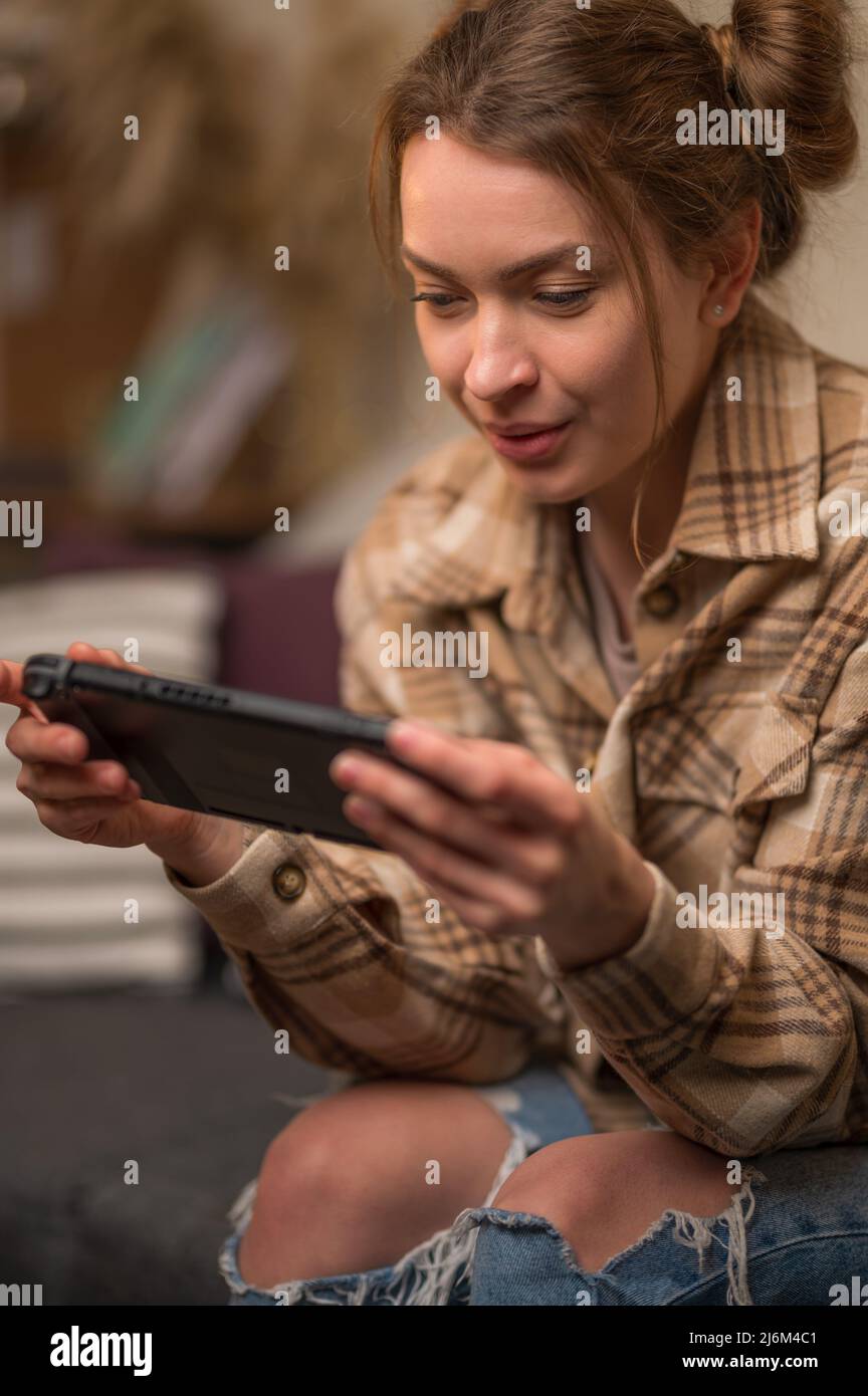 Scatto macro. La ragazza sta tenendo una console di gioco portatile nelle sue mani. Videogiochi, giochi per cellulari, passatempo divertente, giochi online con gli amici, strategia di gioco Foto Stock