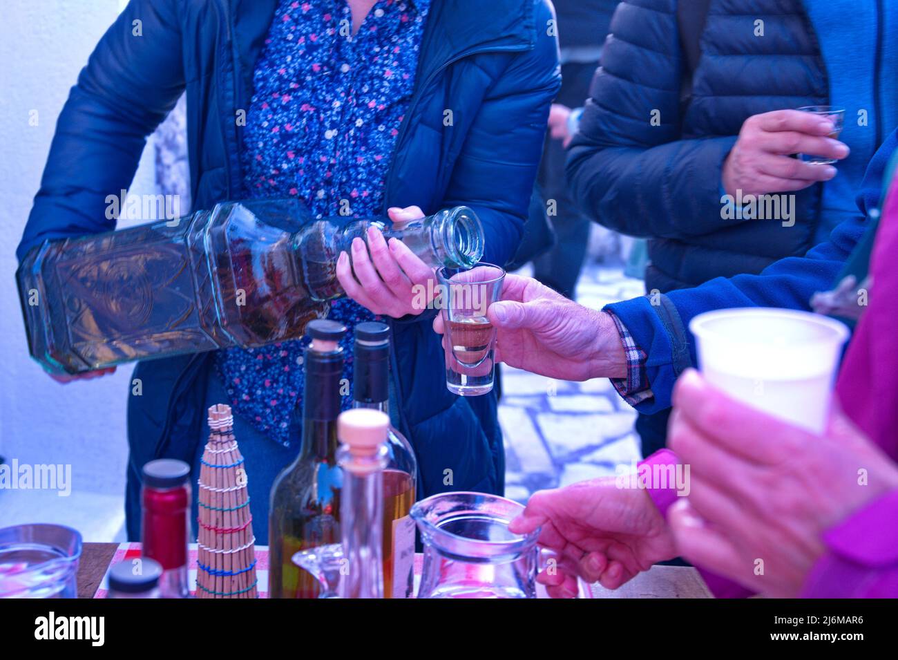 Sezione centrale della donna che versa il brandy dalla bottiglia grande Foto Stock