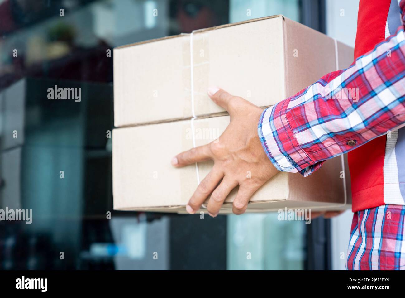 Addetto alla consegna che invia pacchi al cliente, Una persona che indossa una maglietta rossa sta consegnando pacchi ad un cliente soddisfatto. Lavoratore amichevole, di alta qualità Foto Stock