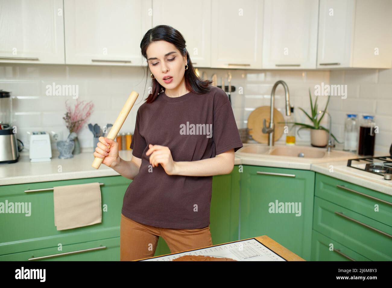 Giovane donna che si aggira intorno, grimacchiando e ballando in cucina. Foto Stock