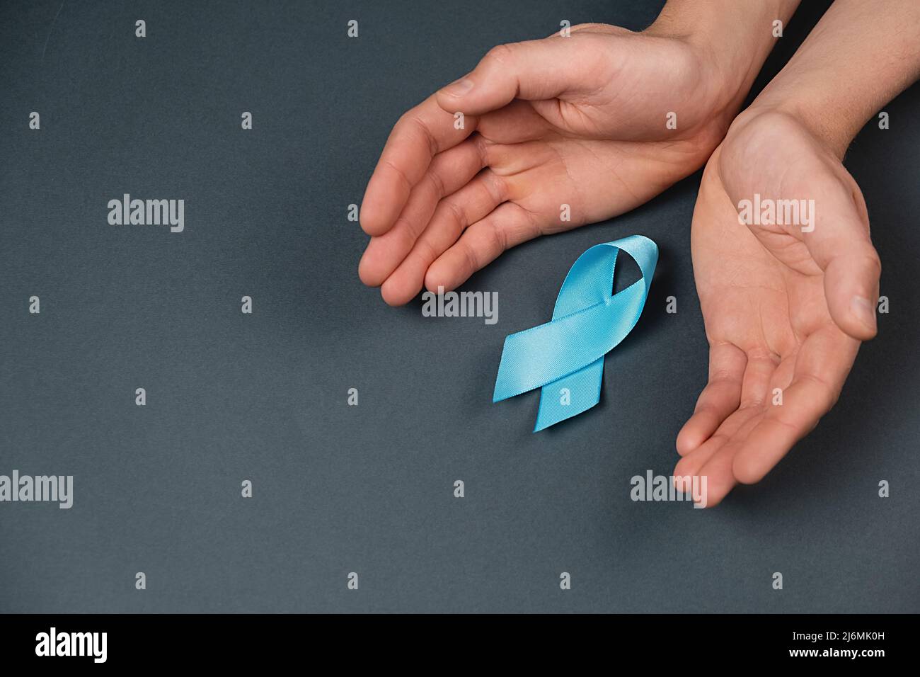 Simbolo per uomini di sostegno. Mani maschili e nastro blu su sfondo grigio. Consapevolezza del cancro della prostata, consapevolezza di salute degli uomini di Movember. Sanità, interno Foto Stock