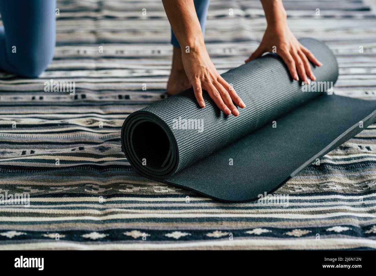 Yoga a casa stile di vita attivo donna rotolamento tappeto esercizio in soggiorno per la meditazione mattina yoga concetto sfondo - persone sane nel giorno Foto Stock