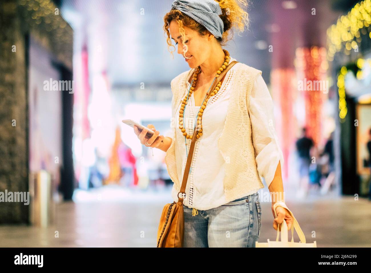 La gente usa il telefono cellulare nel centro commerciale - ragazza graziosa adulta allegra che texting sullo smartphone durante l'attività di shopping - femmina moderna alla moda Foto Stock