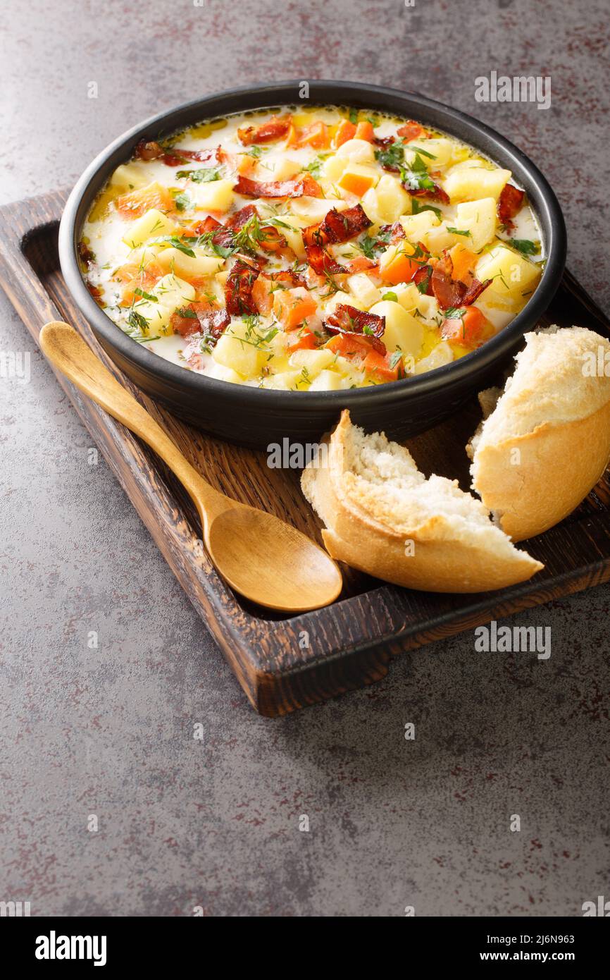 Zuppa polacca di patate con pancetta tradizionale Kartoflanka closeup nel recipiente sul vassoio di legno verticale Foto Stock