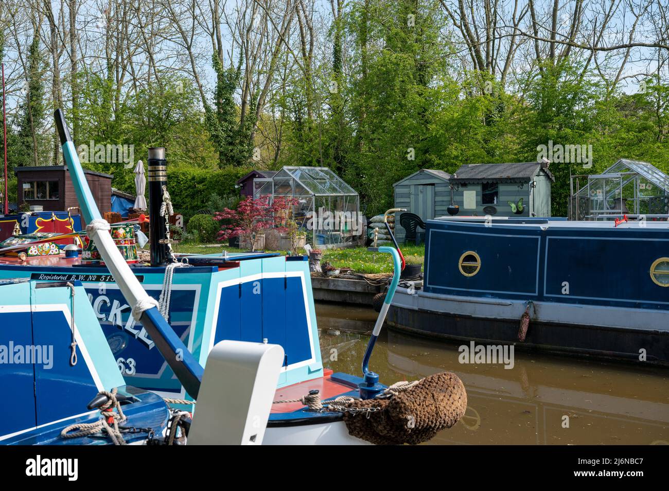 Le barche a remi ormeggiavano accanto ad un giardino ben tenuto appartenente ad un ormeggio residenziale sul canale Shropshire Union a Norbury, Staffordshire Foto Stock