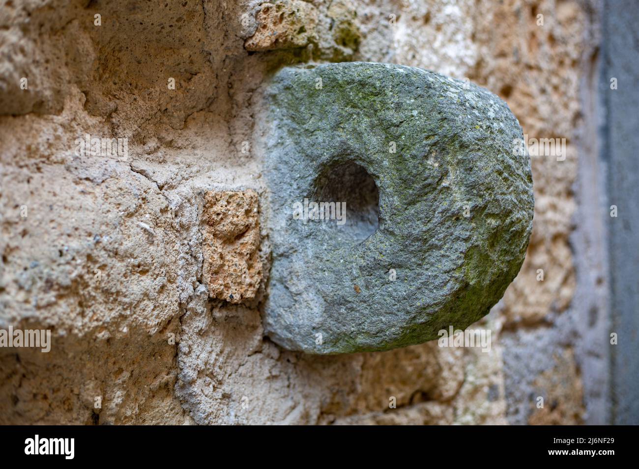 Anello di pietra locale con un buco nel centro per il parcheggio di asino a quattro zampe, mulo, cavallo e mattoni ben costruiti di tuff.Close vulcanico dettaglio di un Foto Stock