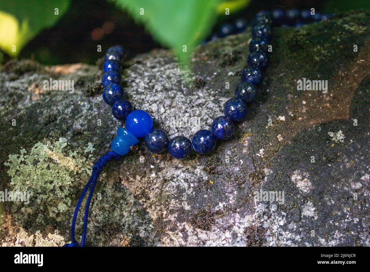 Primo piano di perle blu di mala su pietra. Perle di preghiera buddista per la meditazione japa Foto Stock