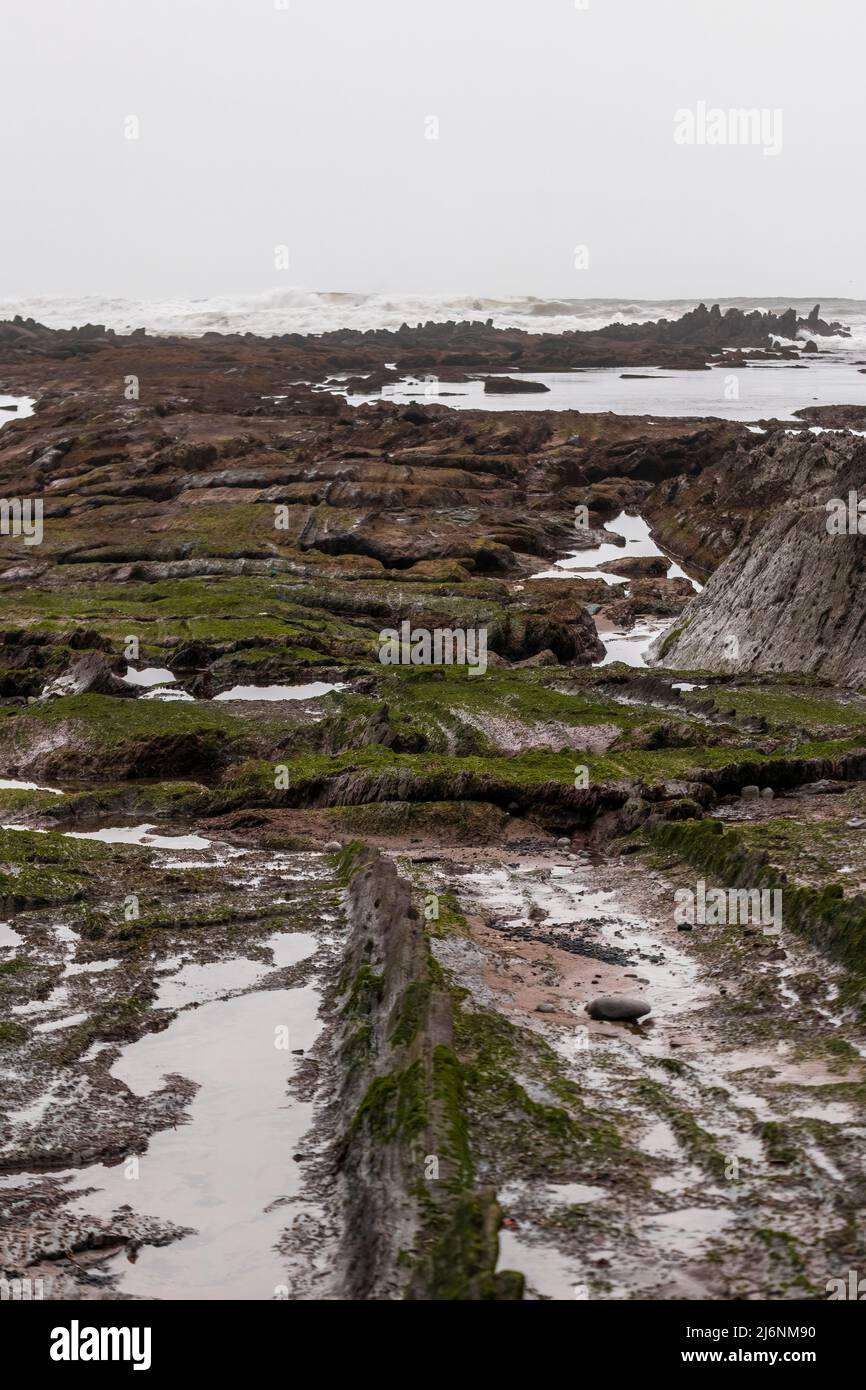 baia rocciosa sulla costa dei paesi baschi nella città di sopelana una giornata nuvolosa Foto Stock