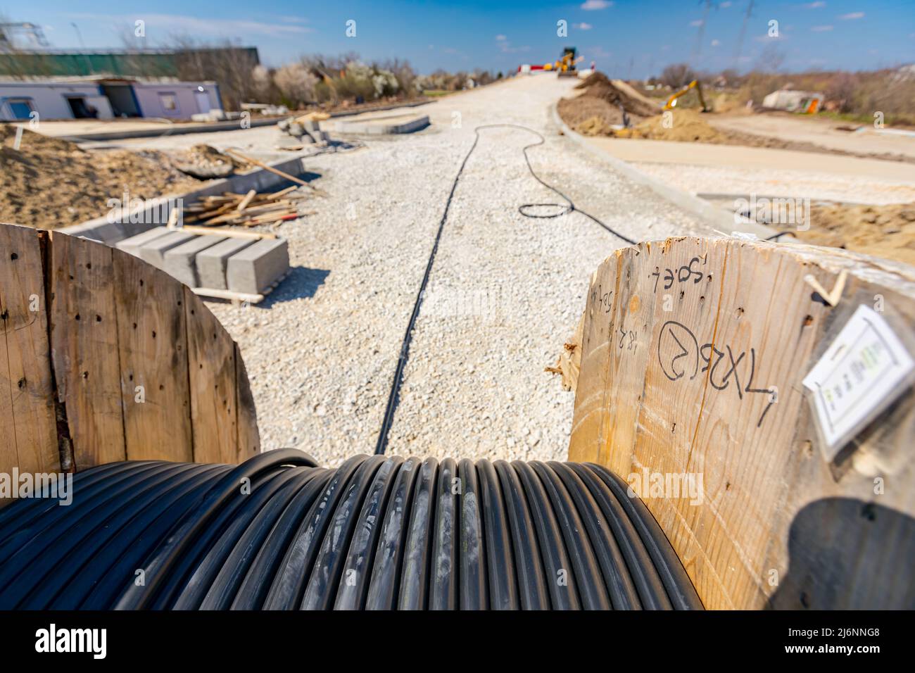 La bobina del cavo dell'aspo si trova sull'assale in legno in cantiere. Foto Stock