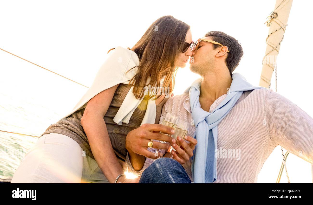 Ricca giovane coppia innamorata in barca a vela baciare al tramonto - concetto di lusso lifestyle che naviga in tutto il mondo - fuoco morbido sul filtro caldo del sole - lente fl Foto Stock