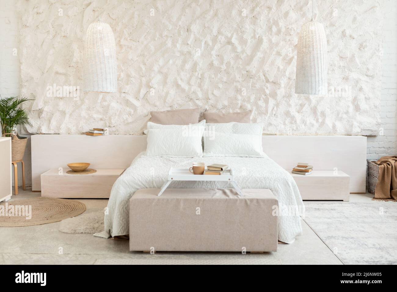 Accogliente letto in moderna camera da letto con pareti bianche e mobili Foto Stock