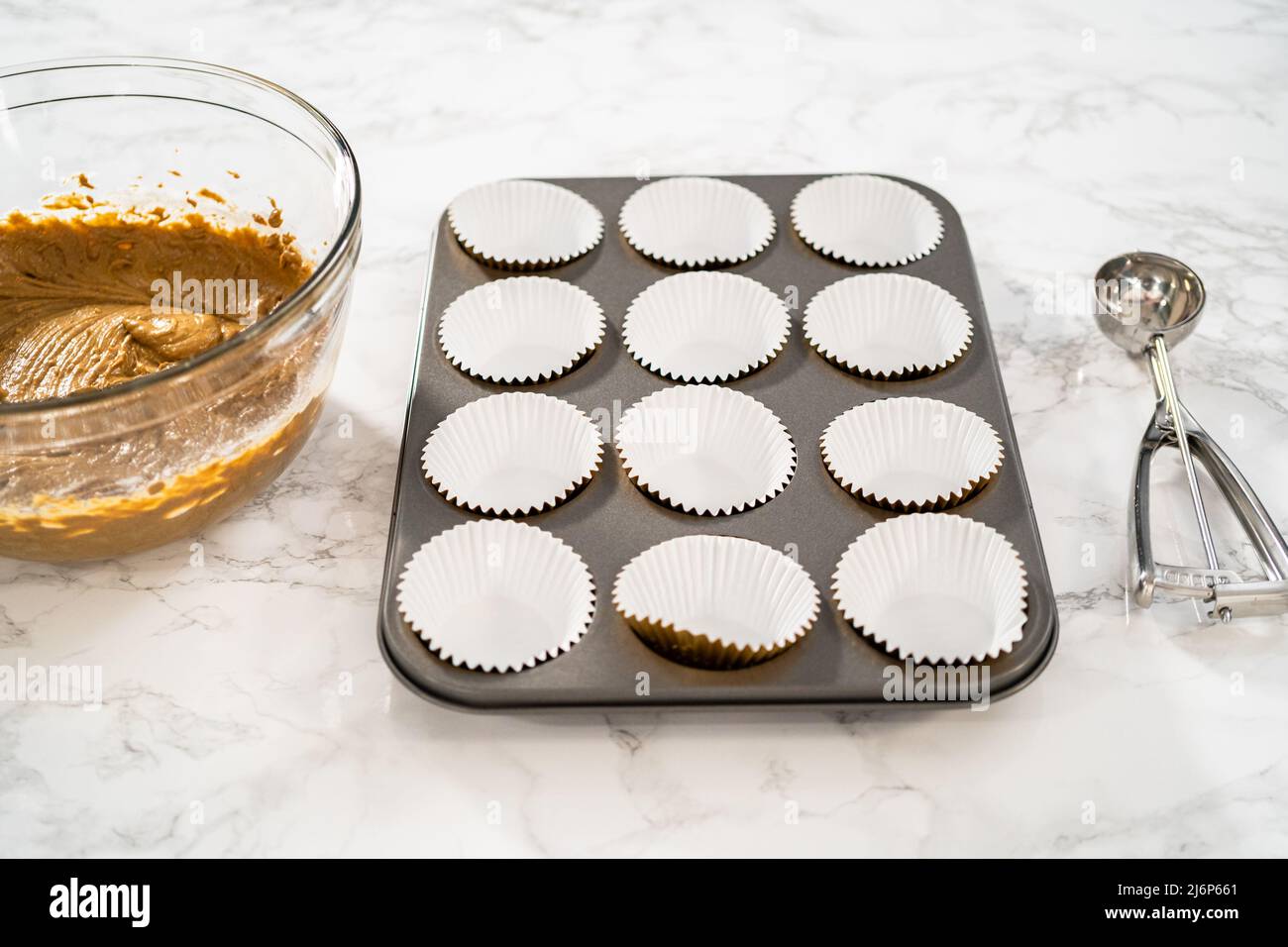 Foderare la teglia per cupcake con i rivestimenti per cupcake in lamina per cuocere i cupcake di pan di zenzero. Foto Stock