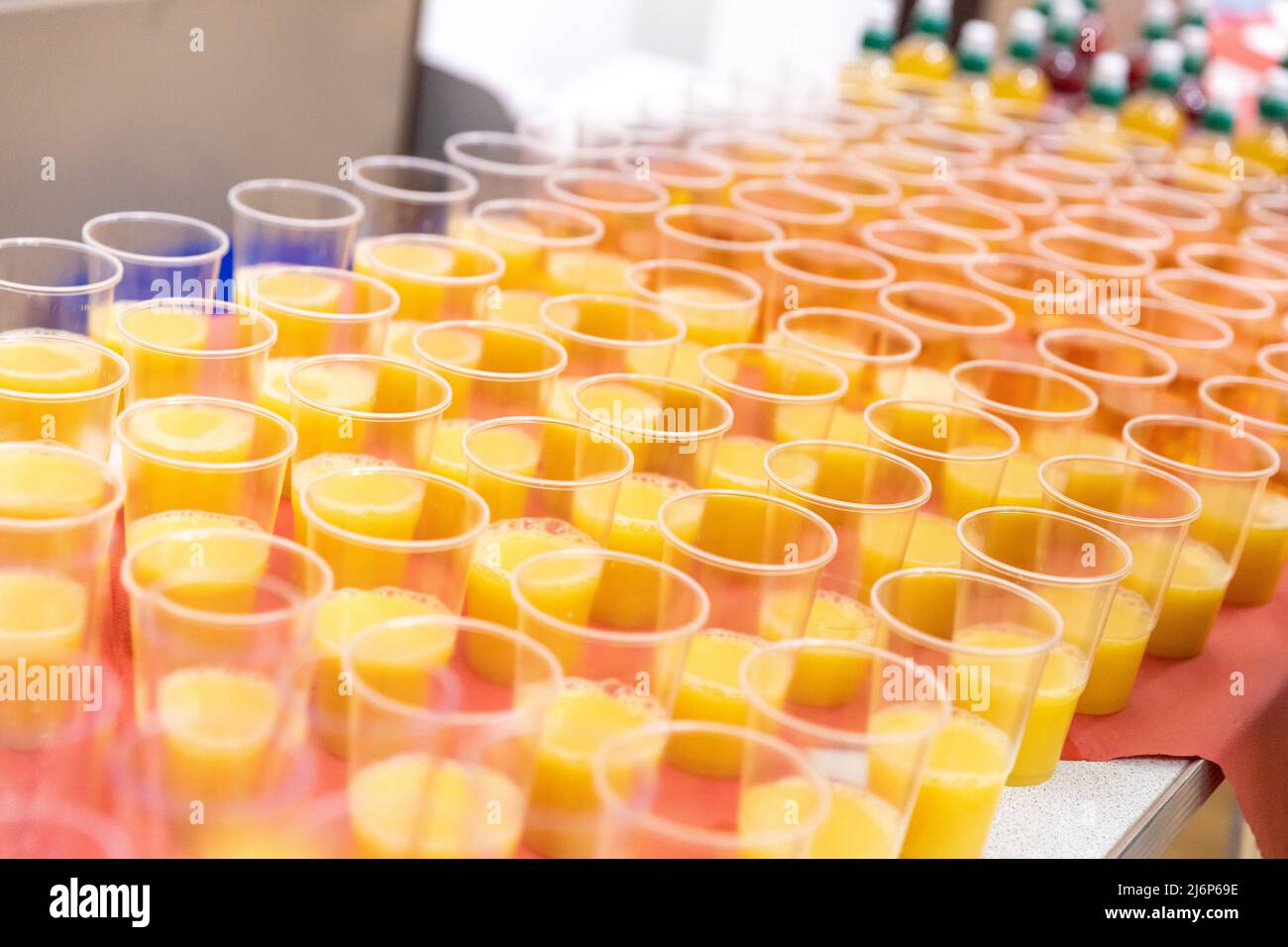 File di bicchieri di plastica con succo d'arancia preparati per una festa di Natale per bambini in un asilo Foto Stock