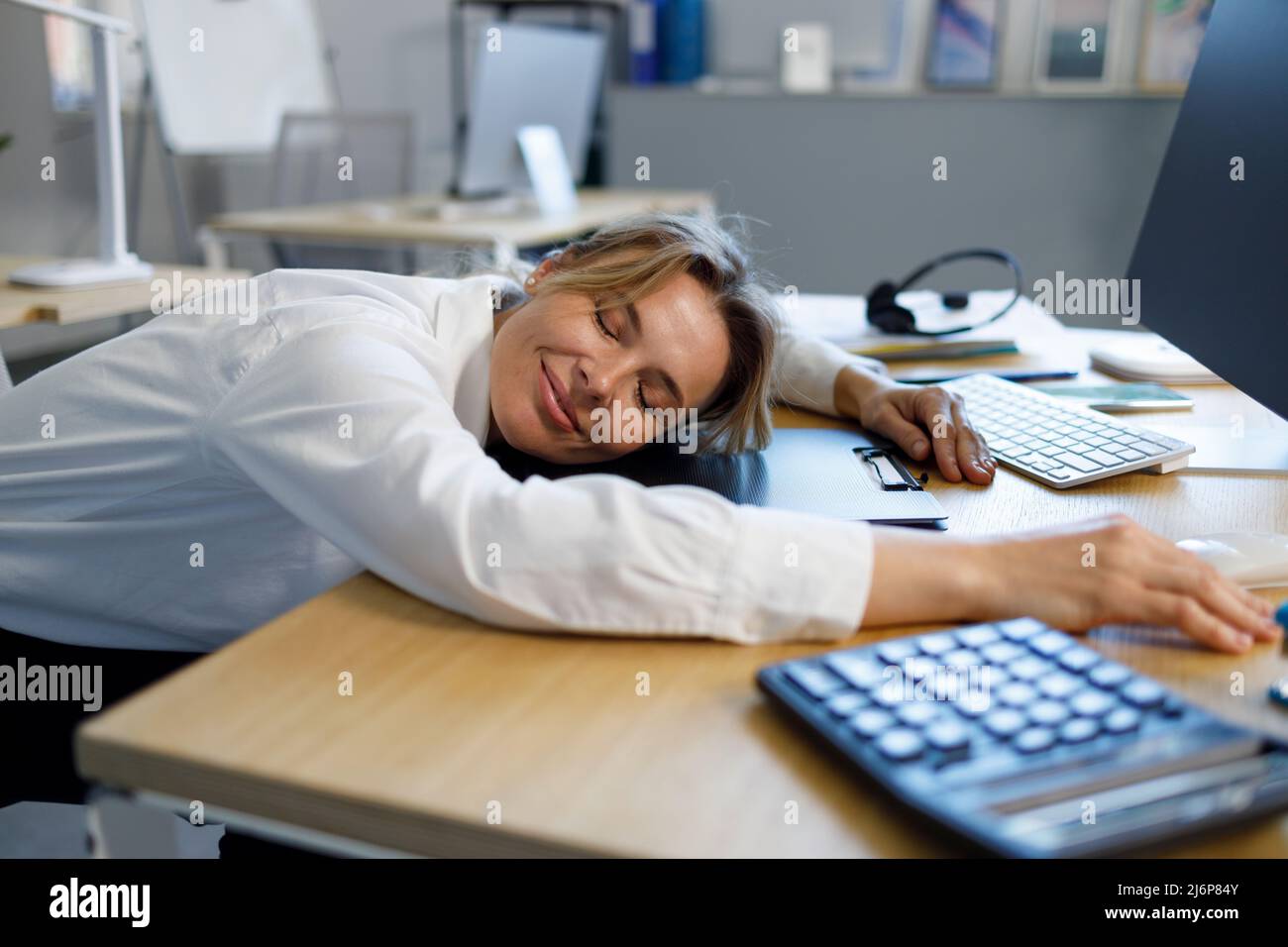 Lavoratore di ufficio femminile con occhi chiusi che si appetta sul posto di lavoro Foto Stock