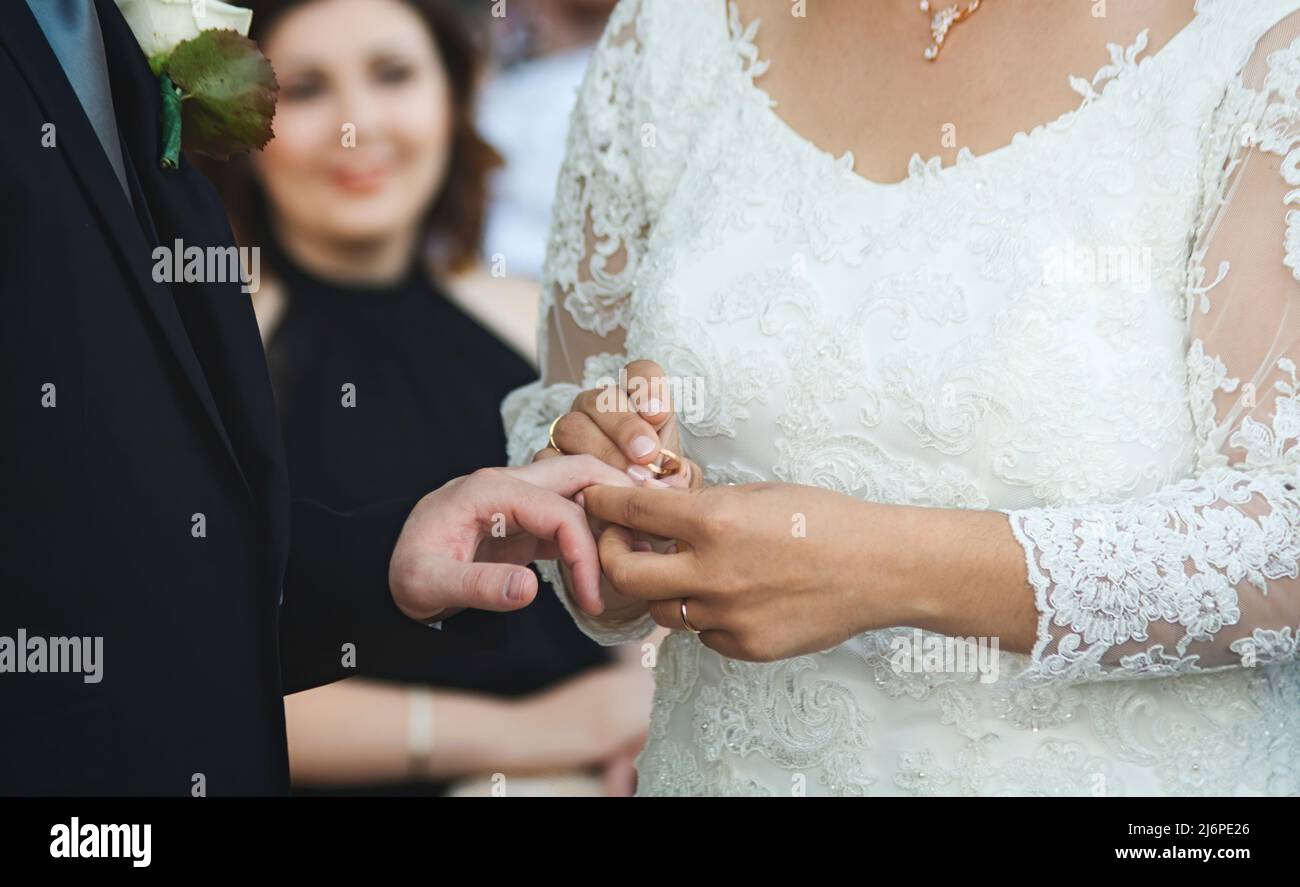 Una coppia che si sposa ad una cerimonia nuziale - la sposa che mette un anello d'oro sul dito dello sposo Foto Stock