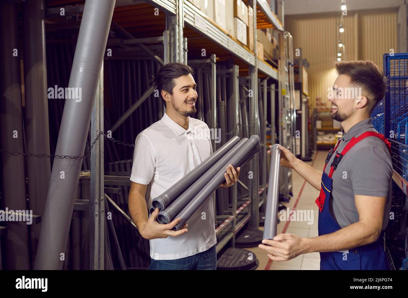 Un venditore sorridente consulta il cliente maschile nell'ipermercato delle costruzioni Foto Stock