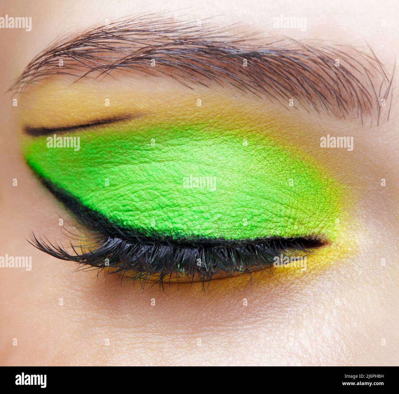 Closeup macro shot di occhio umano femmina chiuso. Donna con trucco viso Vogue. Ragazza con pelle perfetta e ombre occhi verdi e gialli. Foto Stock