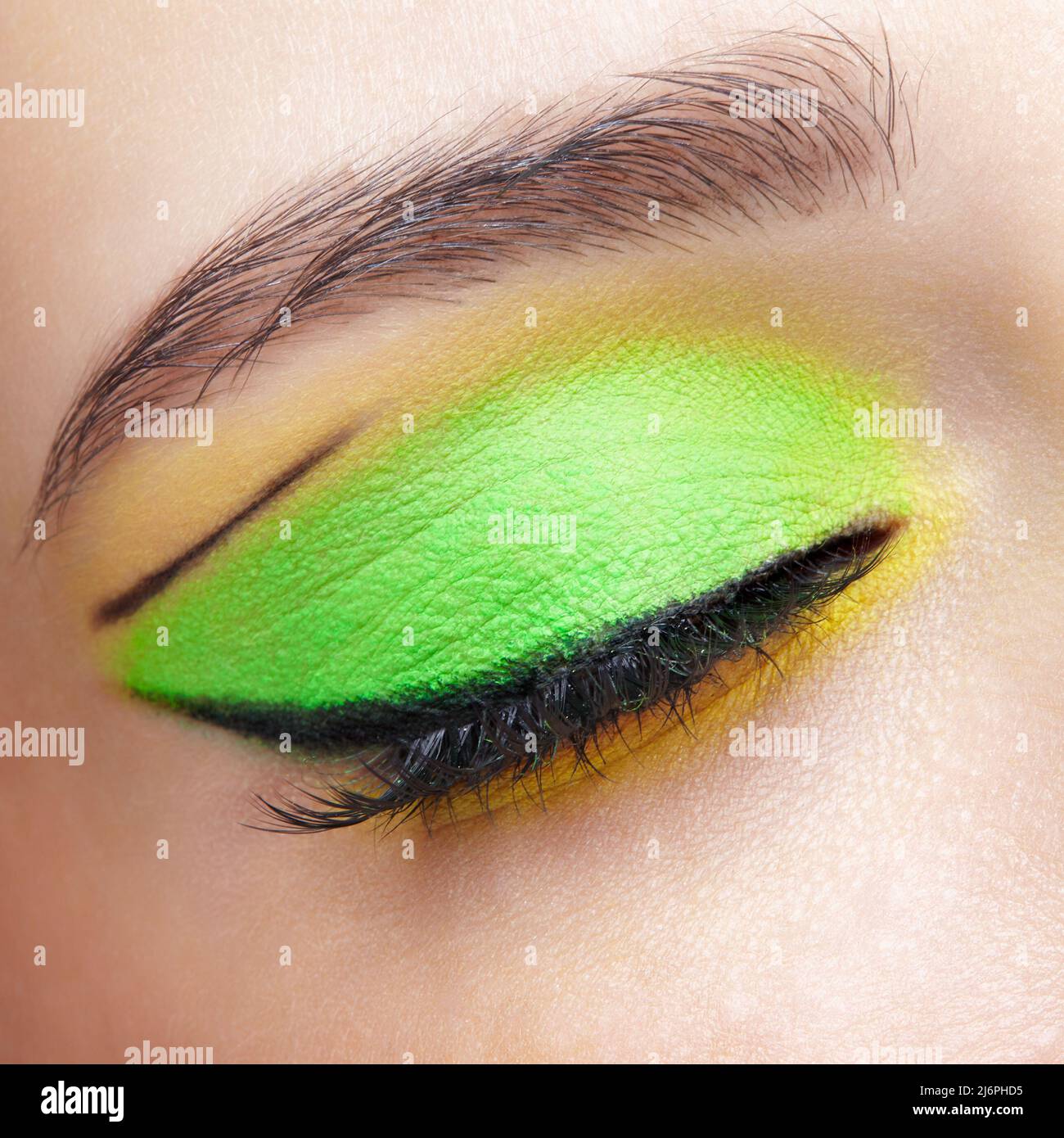 Closeup macro shot di occhio umano femmina chiuso. Donna con trucco viso Vogue. Ragazza con pelle perfetta e ombre occhi verdi e gialli. Foto Stock