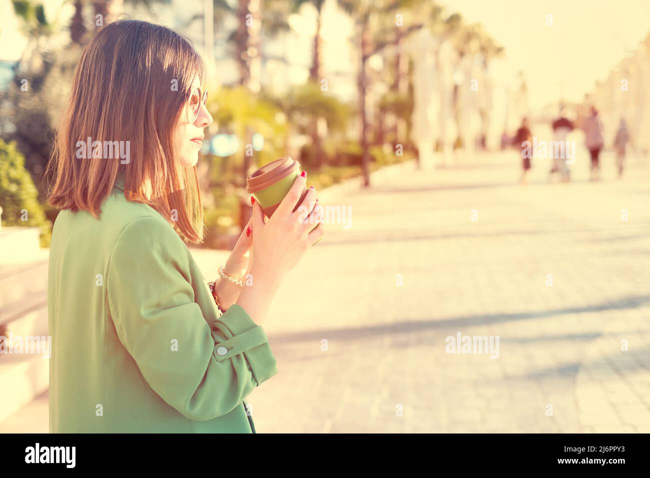 Donna all'aperto che tiene una tazza di caffè di bambù per andare Foto Stock