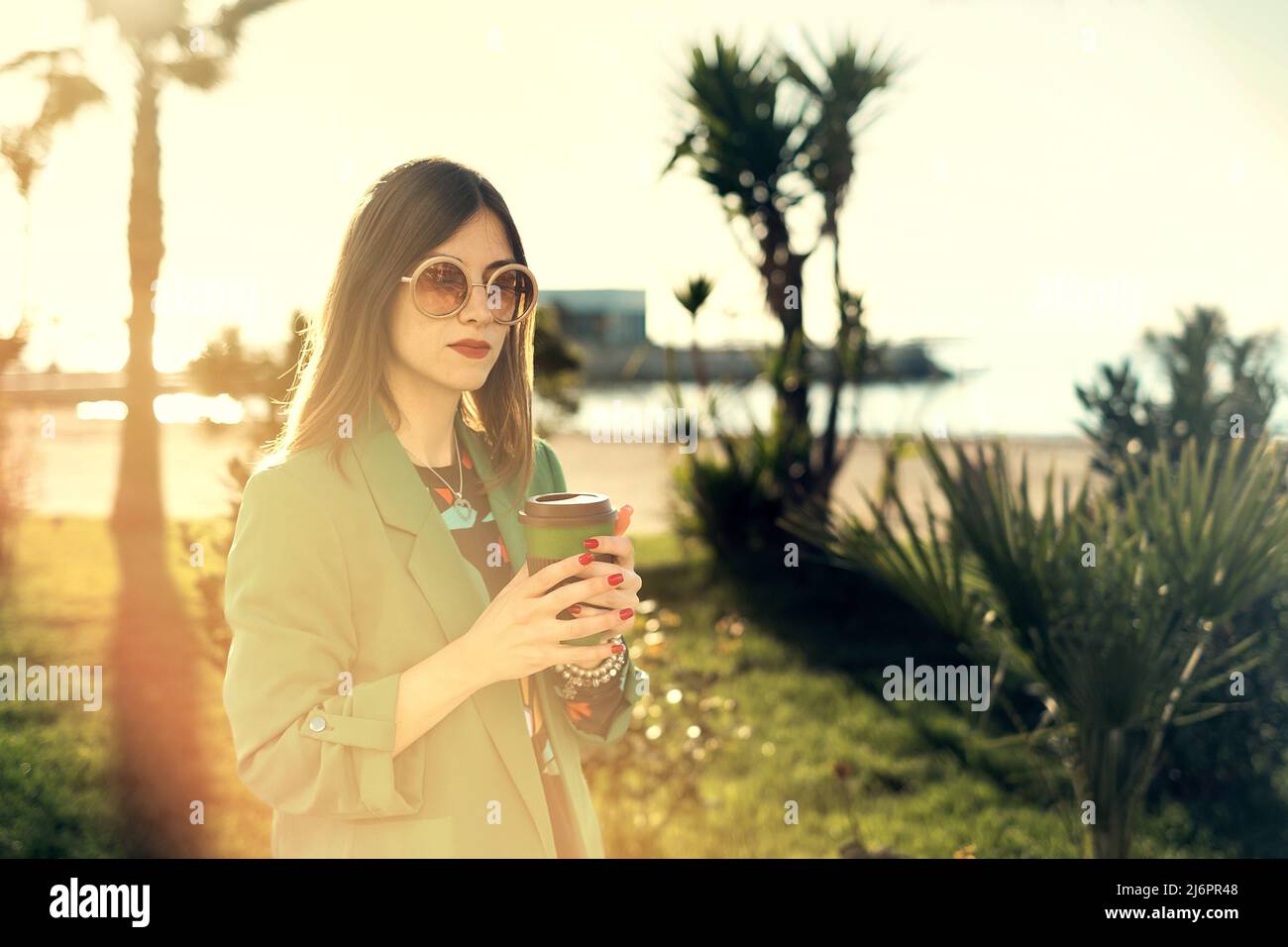 Donna all'aperto che tiene una tazza di caffè di bambù per andare Foto Stock