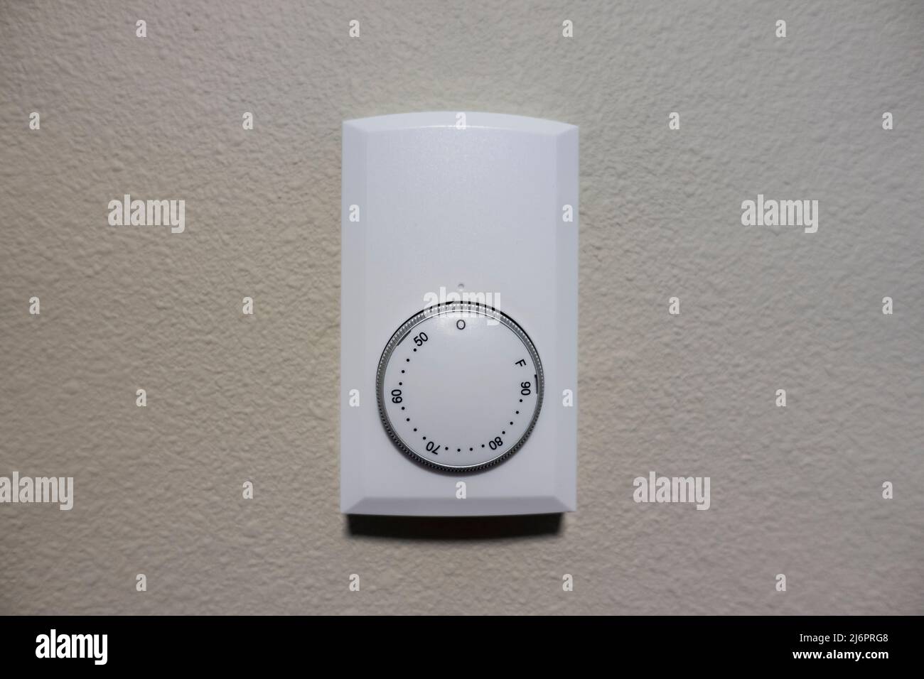 Vista ravvicinata di un pannello di controllo bianco per il raffreddamento e il riscaldamento dell'aria su una parete bianca all'interno di una casa Foto Stock