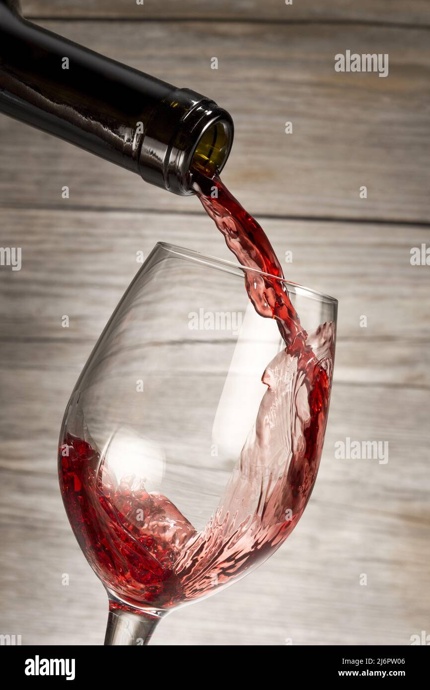 bottiglia di vino rosso in un bicchiere isolato su sfondo rustico in legno Foto Stock
