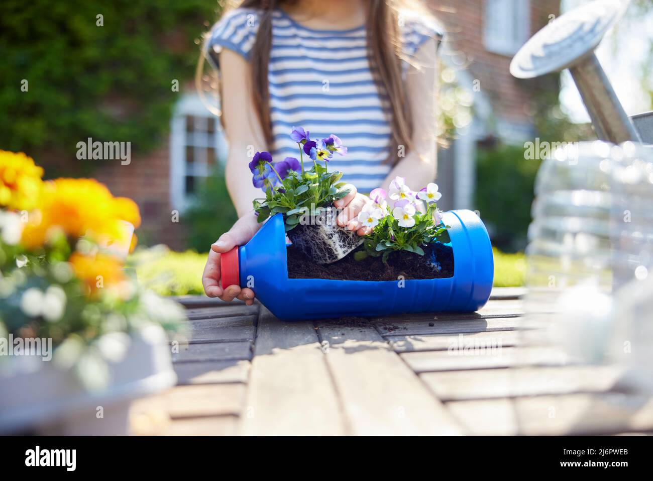 Primo piano di Girl Making Recycled Plant Holder da plastica bottiglia imballaggio rifiuti in giardino a casa Foto Stock