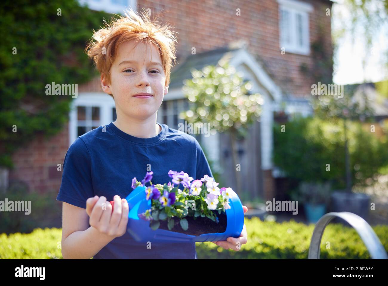 Ritratto di Boy Holding Casa Reciclato pianta Titolare da plastica bottiglia imballaggio rifiuti in giardino a casa Foto Stock