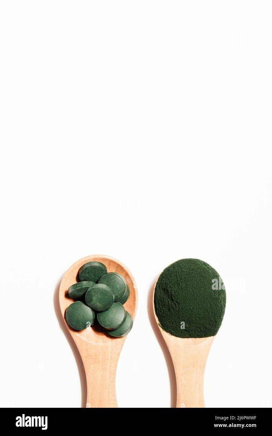 additivi naturali e superfood. polvere di alghe spirulina verde e pillole su cucchiaio di legno su sfondo bianco. concetto sano. spazio copia cibo biologico Foto Stock