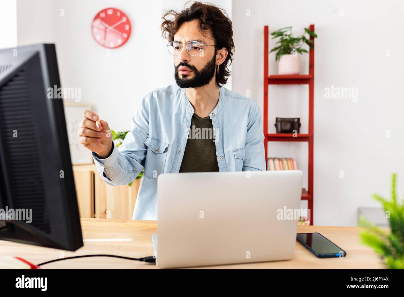 Il giovane freelance hipster che lavora si è concentrato sul computer portatile da casa Foto Stock