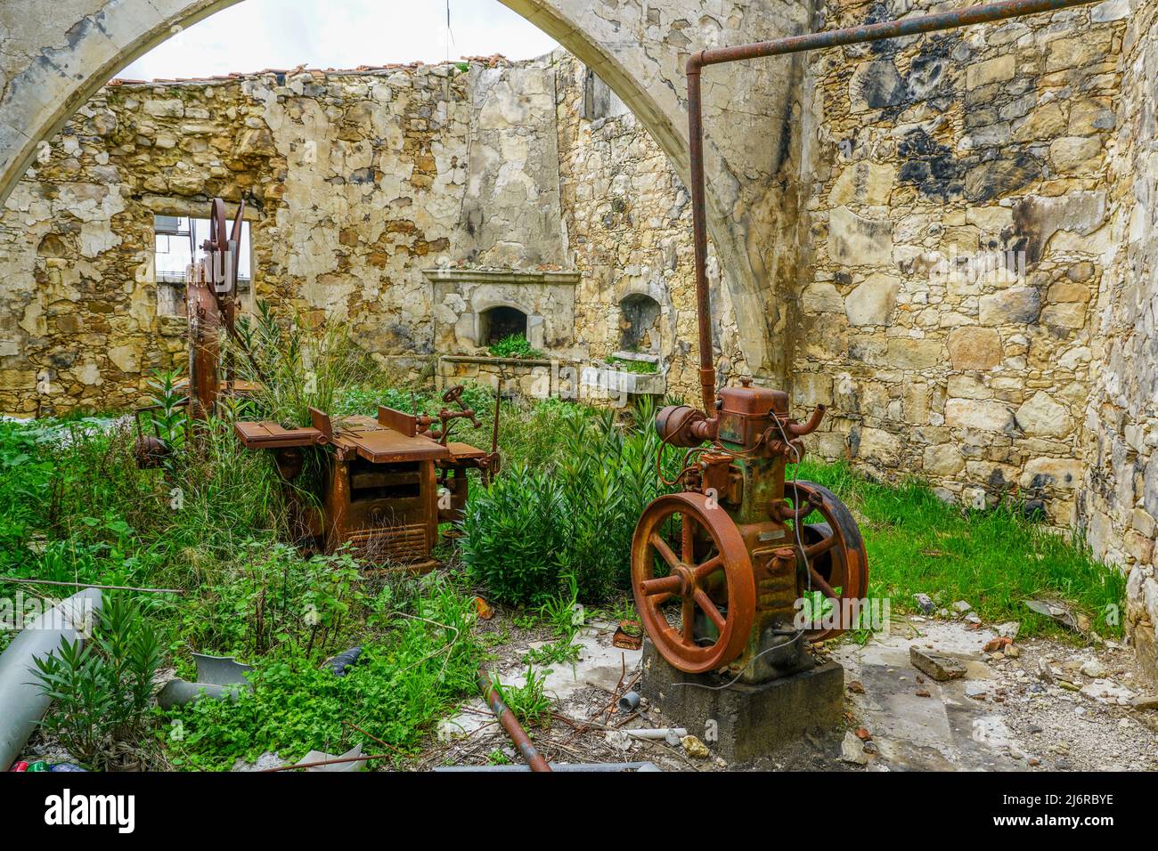 Interno di una vecchia officina artigianale abbandonata con banchi da lavoro e motori arrugginiti Foto Stock