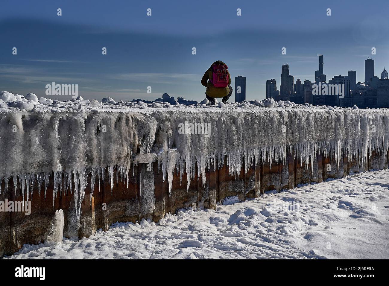 vista ad angolo basso del fotografo occasionale, del ghiaccio e della neve e della città sullo sfondo Foto Stock