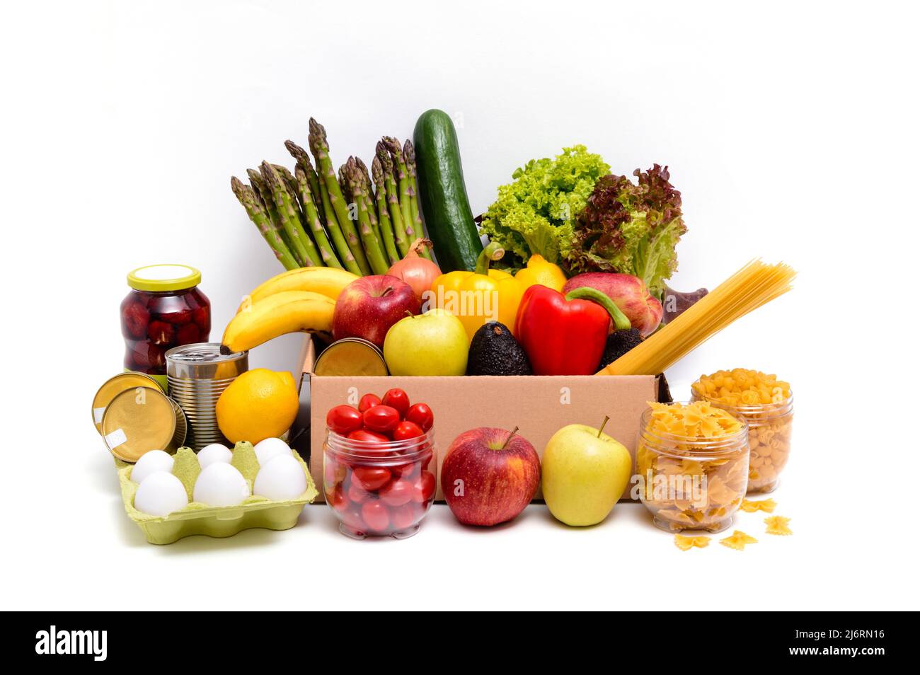 Scatola di cartone con frutta e verdura fresca, uova, pasta e cibi in scatola. Concetto di donazione o consegna di cibo. Prodotti alimentari vegetariani, isolati Foto Stock