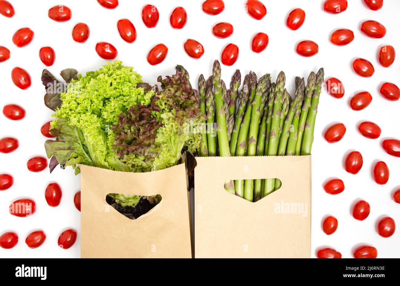 Verdure verdi e rosse - lattuga, asparagi e pomodori ciliegini isolati su sfondo bianco. Dieta sana, prodotti vegetariani, negozi di alimentari Foto Stock