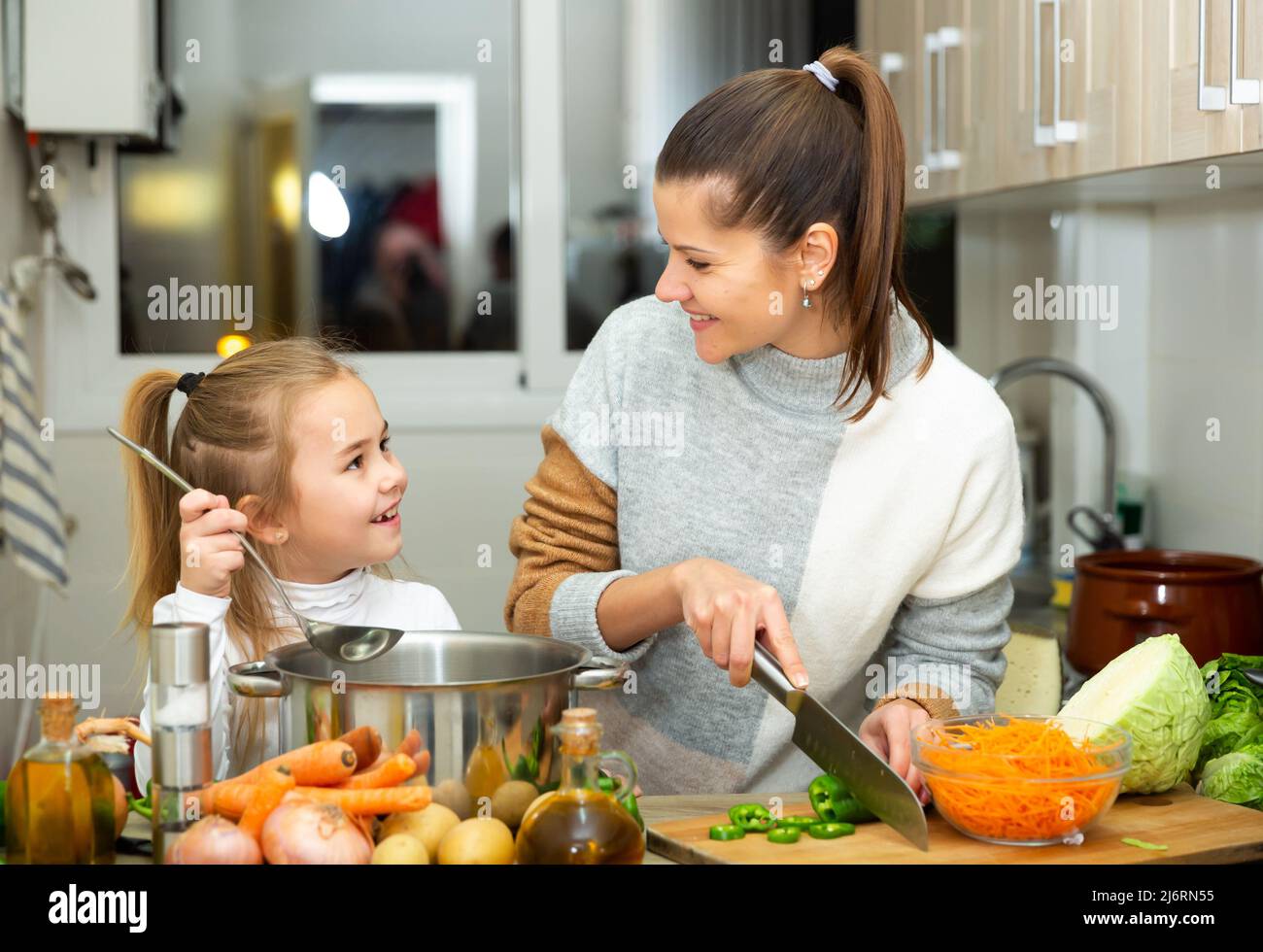 Madre e bambina che preparano la zuppa insieme a casa, Foto Stock