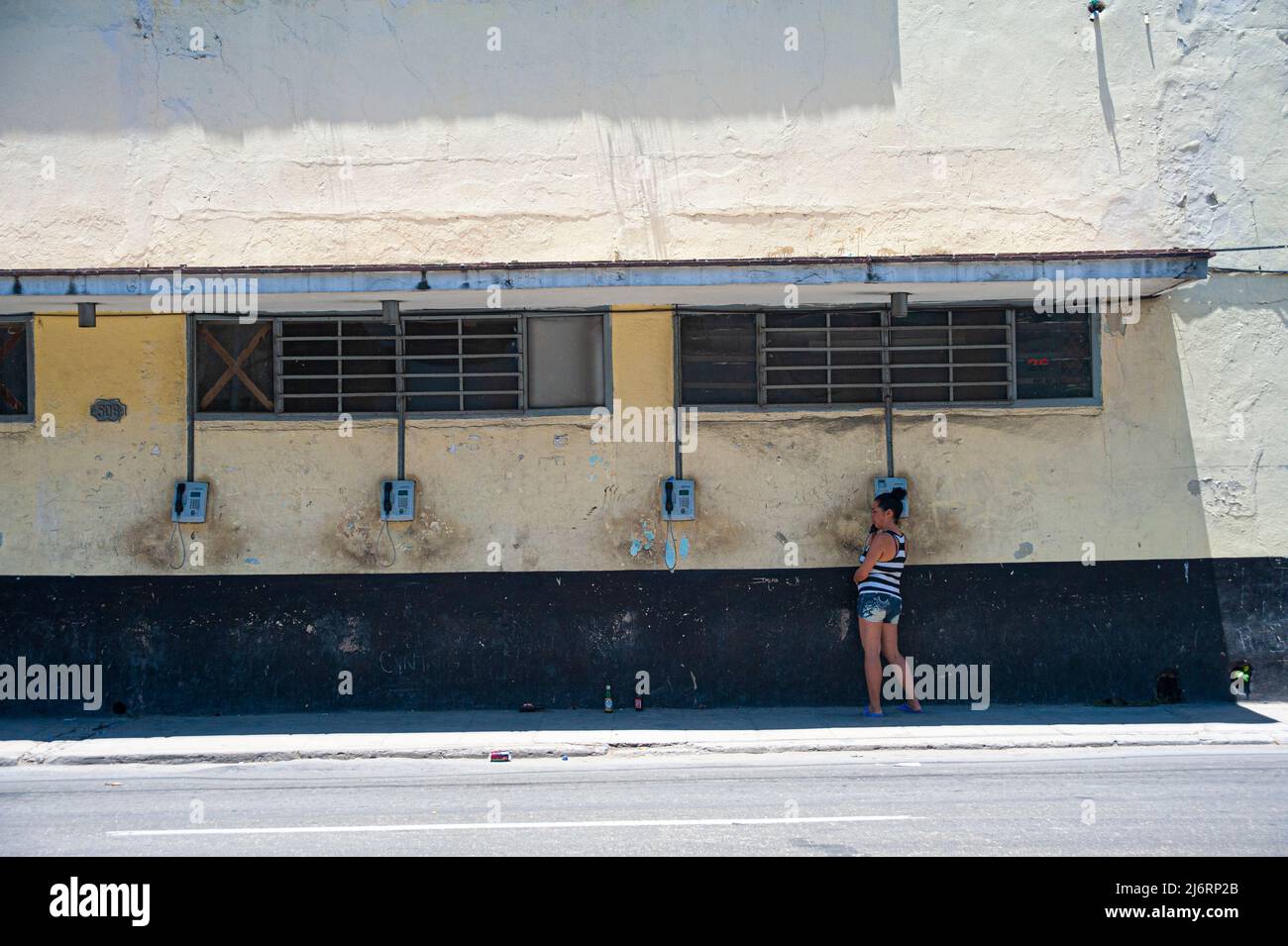 La donna parla di un vecchio telefono pubblico a pagamento obsoleto a l'Avana, Cuba. Foto Stock