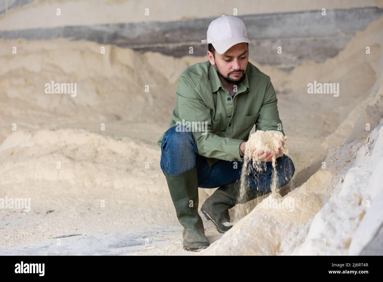 Coltivatore che squatting a mucchio di farina di mais Foto Stock