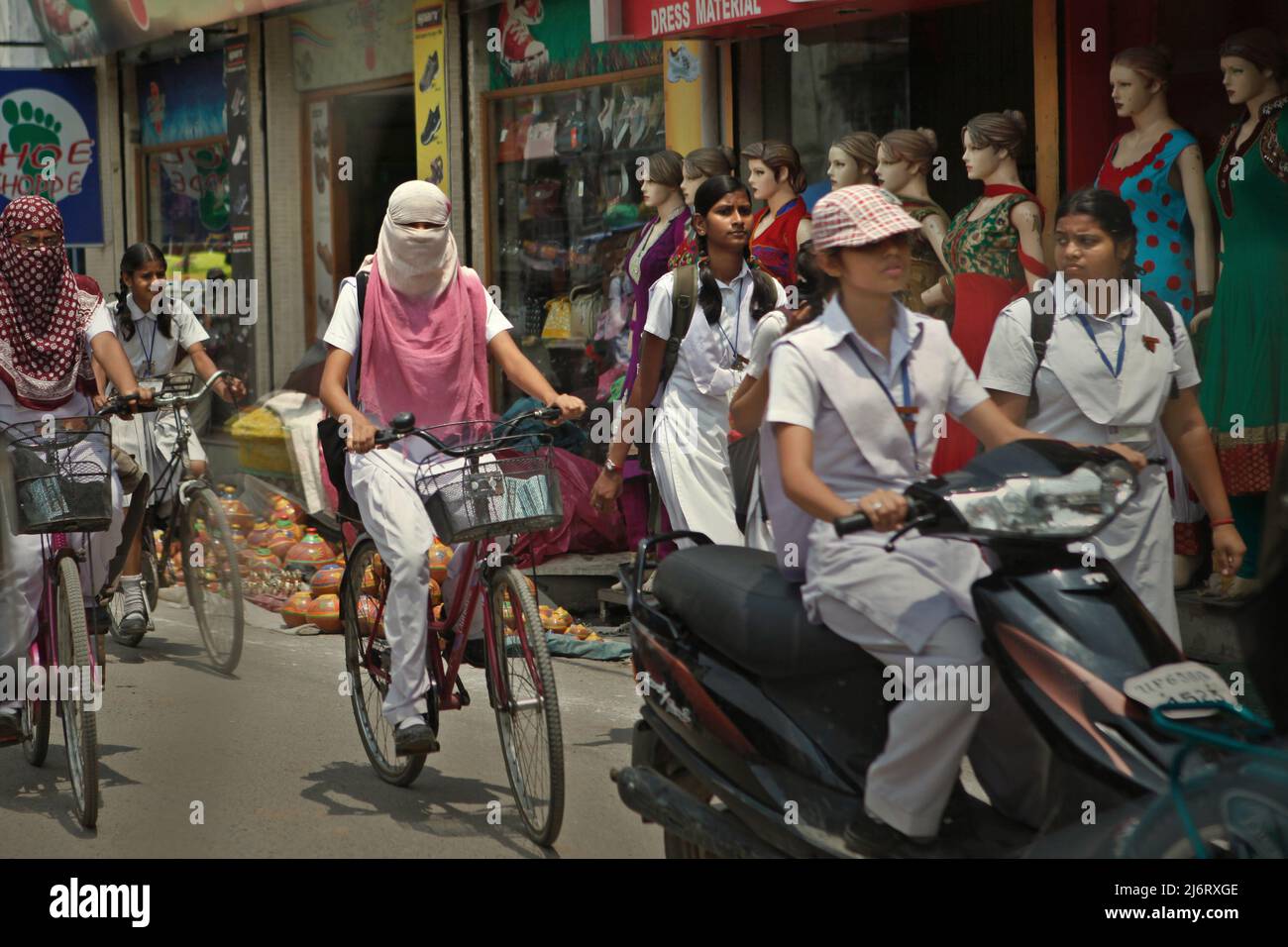 Le studentesse pedalano lungo una strada attraverso il traffico pesante a Varanasi, Uttar Pradesh, India. Foto Stock