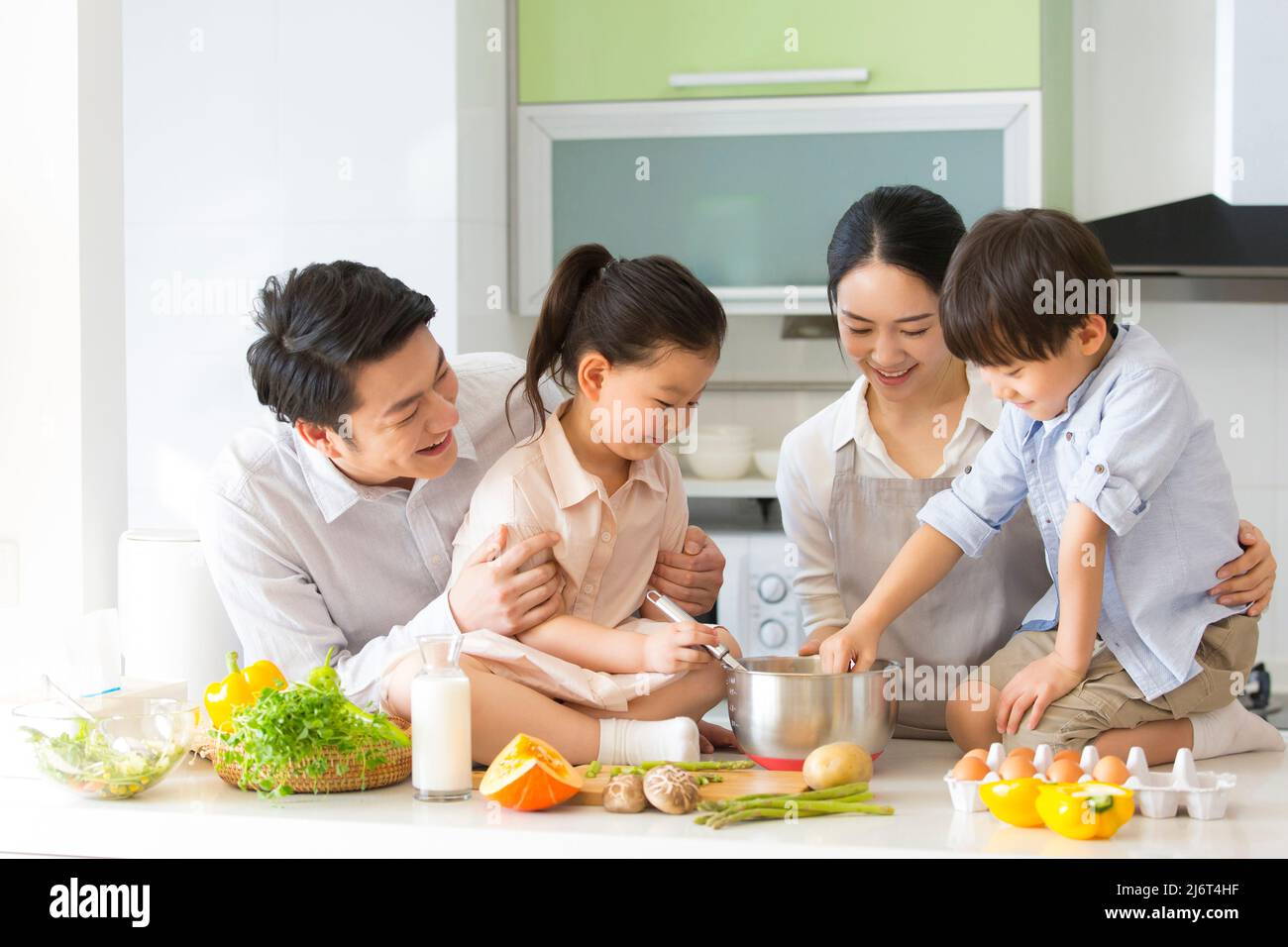 Famiglia cucina parentage. I giovani genitori insegnano a due preschoolers come cucinare. - foto di scorta Foto Stock