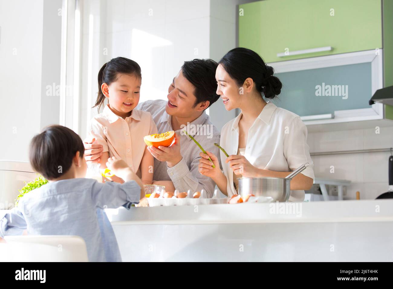 Famiglia cucina parentage. I giovani genitori giocano con loro figlio e figlia mentre cucinano insieme. - foto di scorta Foto Stock