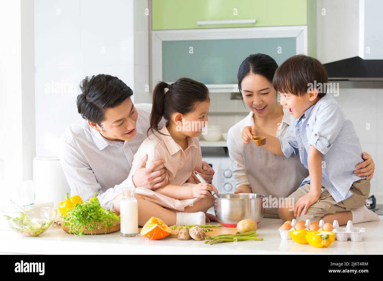 Famiglia cucina parentage. I giovani genitori insegnano a due preschoolers come cucinare. - foto di scorta Foto Stock