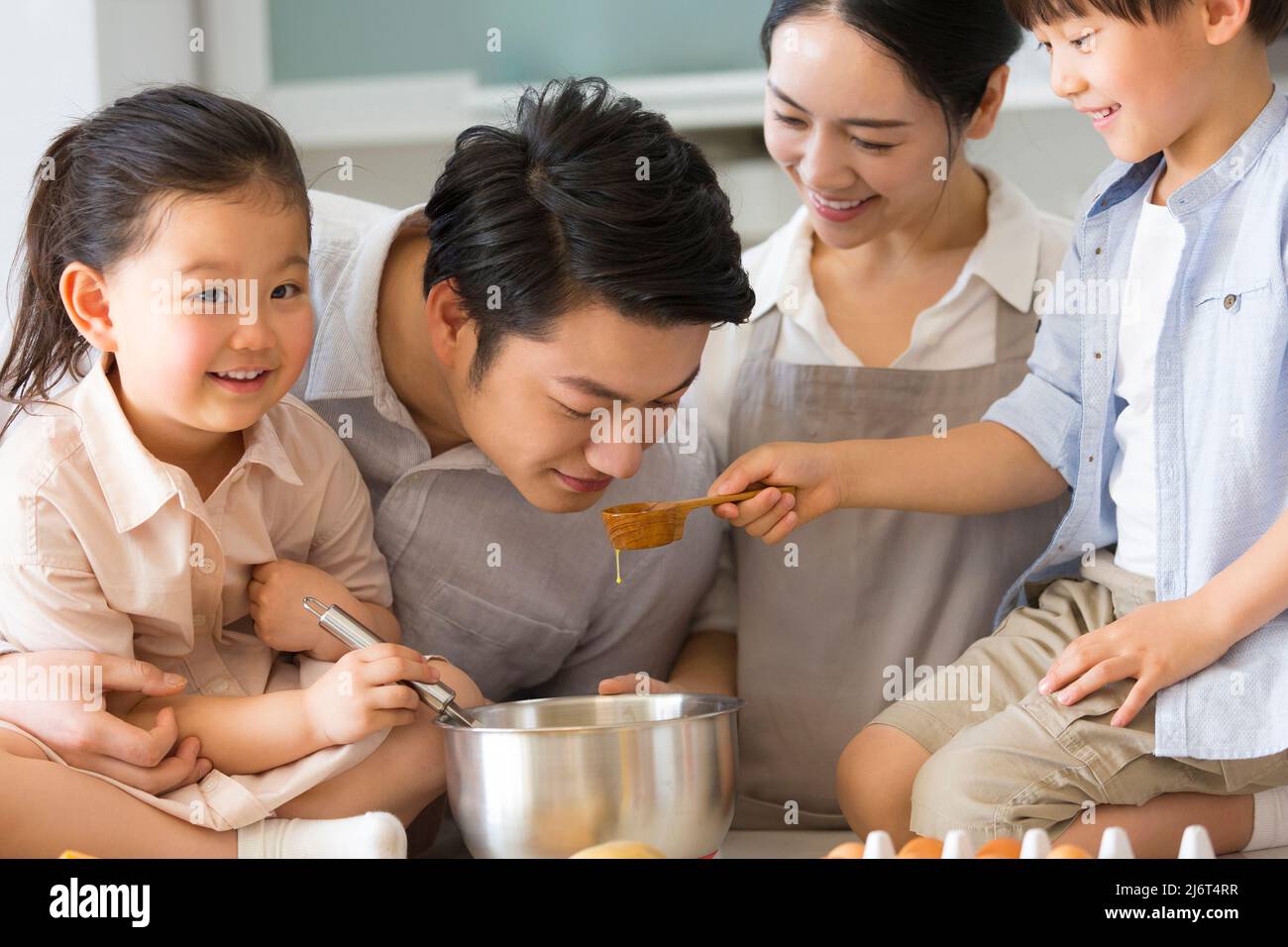 Parentage. I giovani genitori insegnano ai bambini come preparare i piatti. Il ragazzo prende un cucchiaio e lo consegna al padre per odorare. - foto di scorta Foto Stock