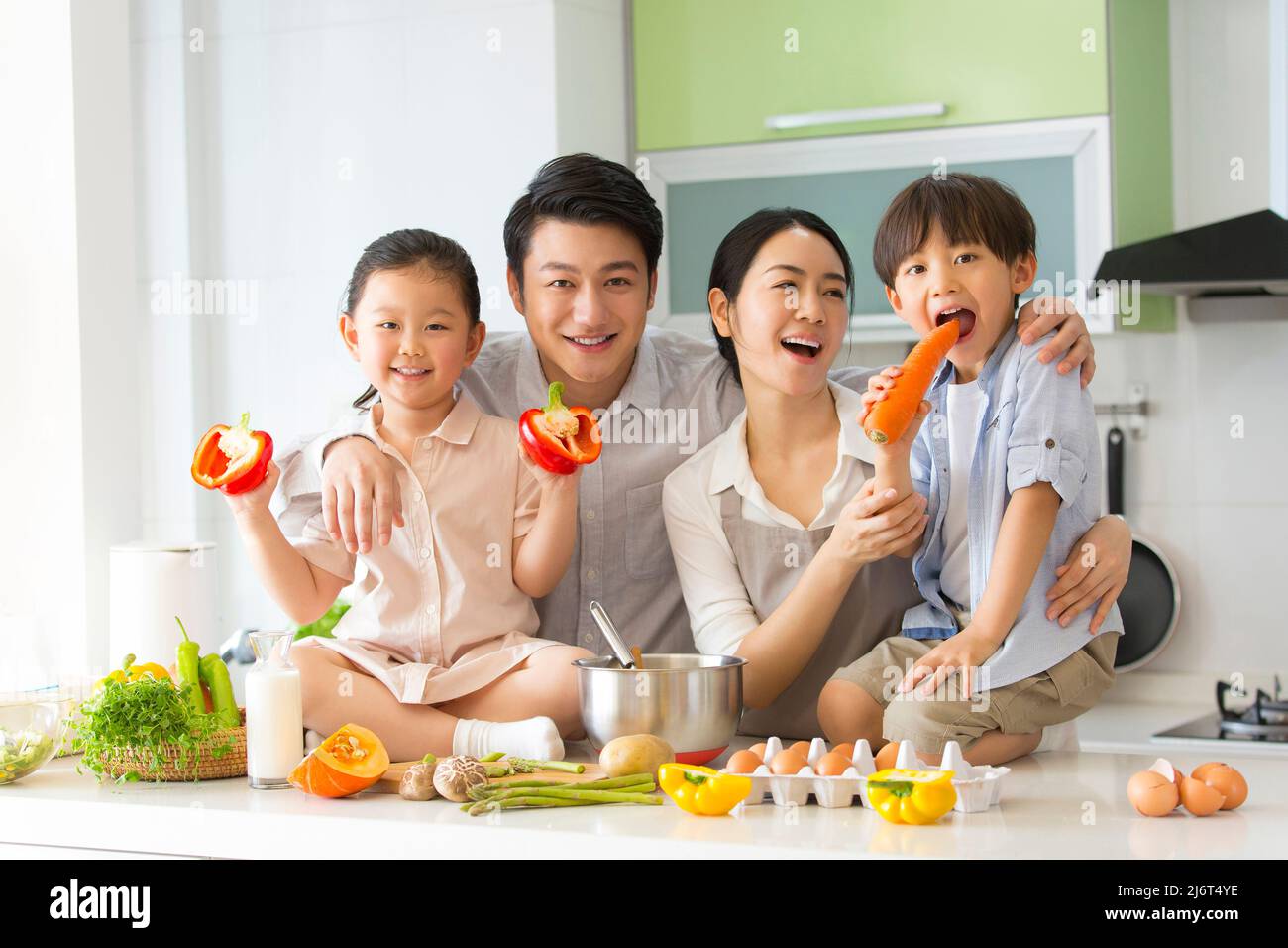 Parentage. I giovani genitori insegnano a due preschoolers come cucinare e i bambini cattivi giocano con le verdure. - foto di scorta Foto Stock
